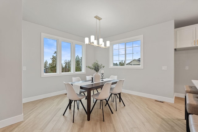 dining area with a wealth of natural light, a notable chandelier, and light hardwood / wood-style flooring