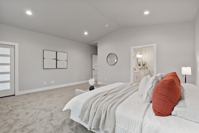 bedroom featuring ensuite bath, lofted ceiling, and light carpet