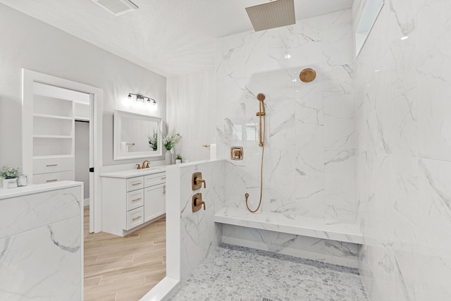 bathroom featuring tiled shower and vanity