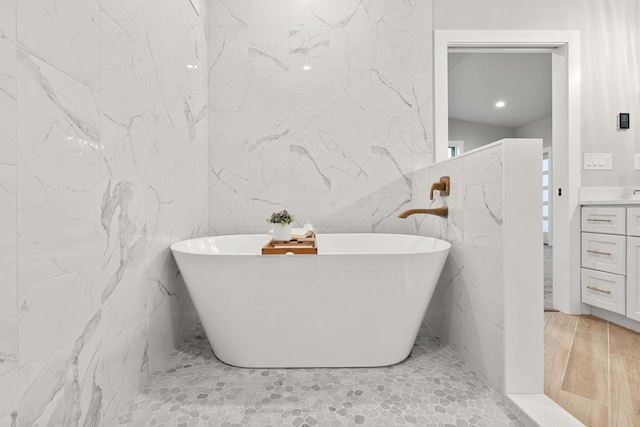 bathroom with vanity, a bathtub, and tile walls