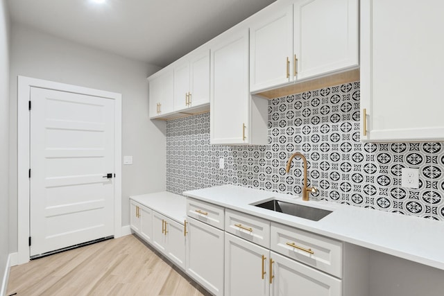 kitchen featuring tasteful backsplash, sink, white cabinets, and light wood-type flooring