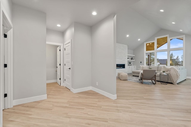 hall with built in shelves, high vaulted ceiling, and light hardwood / wood-style flooring