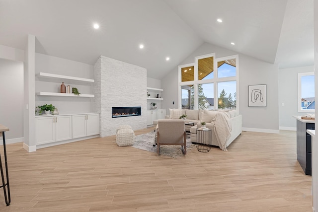 living room featuring a stone fireplace, high vaulted ceiling, and built in shelves