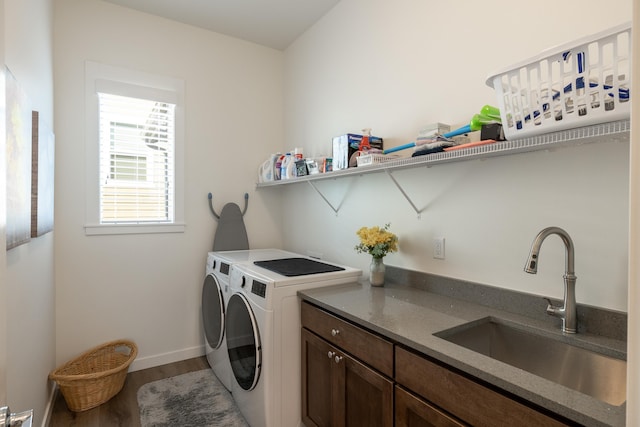 clothes washing area with washer and clothes dryer, sink, cabinets, and hardwood / wood-style flooring