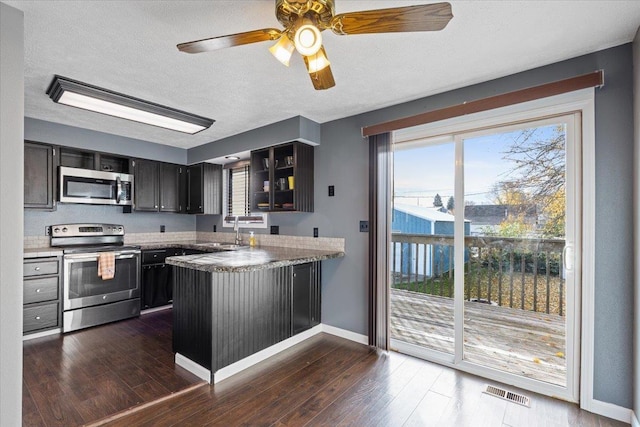 kitchen with ceiling fan, sink, kitchen peninsula, a textured ceiling, and appliances with stainless steel finishes