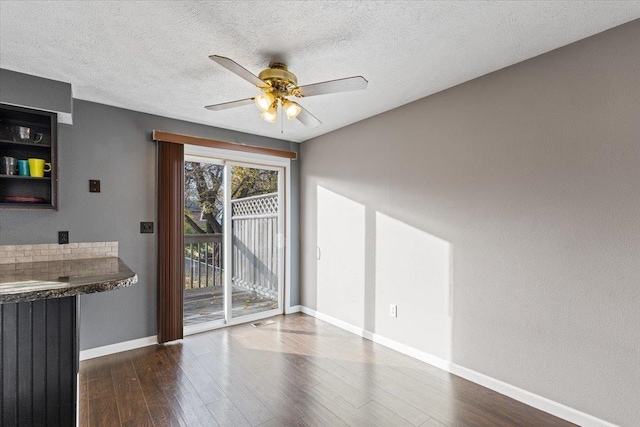 interior space featuring a textured ceiling, ceiling fan, and dark wood-type flooring