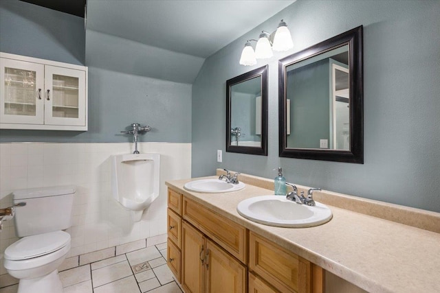 bathroom featuring tile patterned flooring, vaulted ceiling, toilet, vanity, and tile walls