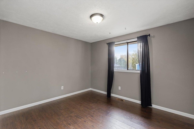 unfurnished room with a textured ceiling and dark wood-type flooring