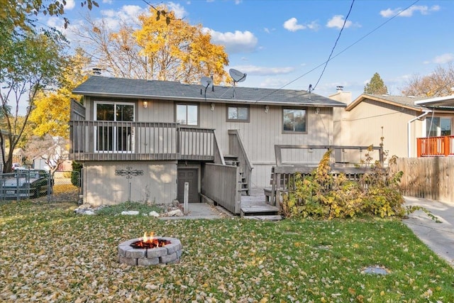 back of house with a fire pit, a yard, and a wooden deck