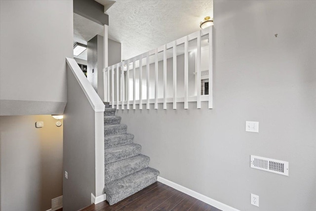 staircase with hardwood / wood-style floors and a textured ceiling