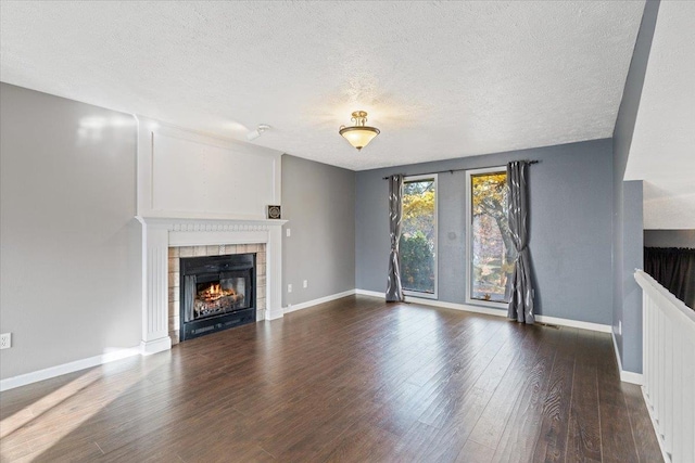 unfurnished living room with a textured ceiling, hardwood / wood-style flooring, and a tiled fireplace