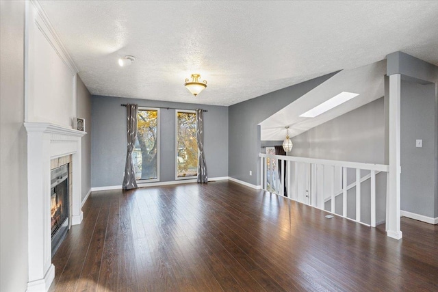 unfurnished living room featuring lofted ceiling with skylight, dark wood-type flooring, and a textured ceiling