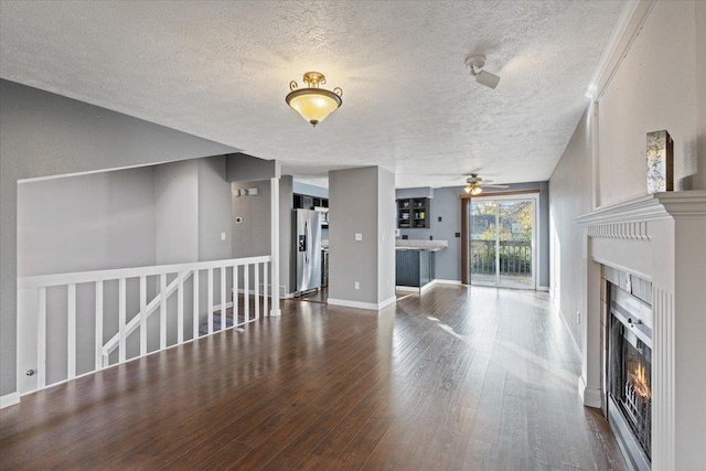 unfurnished living room with ceiling fan, a textured ceiling, and hardwood / wood-style flooring