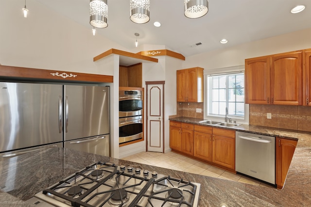 kitchen with backsplash, dark stone counters, stainless steel appliances, vaulted ceiling, and sink