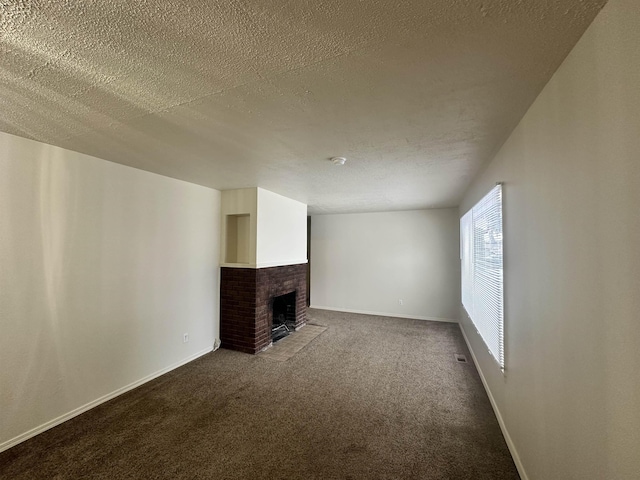 unfurnished living room with a fireplace, a textured ceiling, and dark carpet