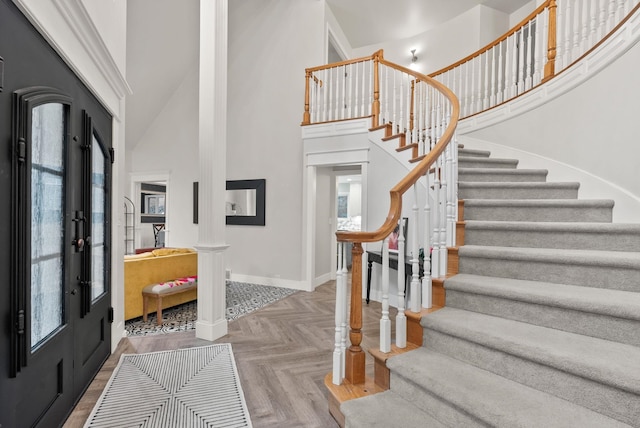 foyer featuring french doors, a towering ceiling, and parquet floors