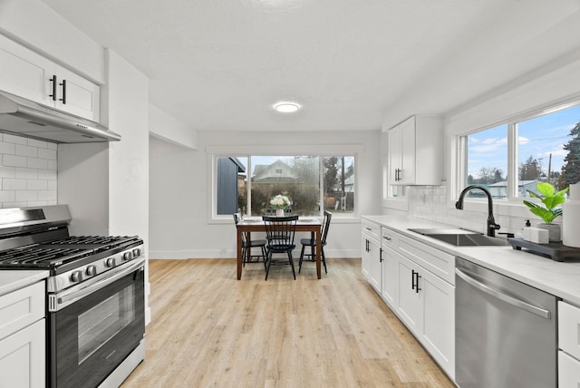 kitchen with tasteful backsplash, sink, white cabinets, and appliances with stainless steel finishes