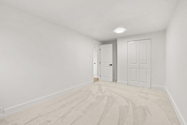 unfurnished bedroom featuring a closet and light colored carpet