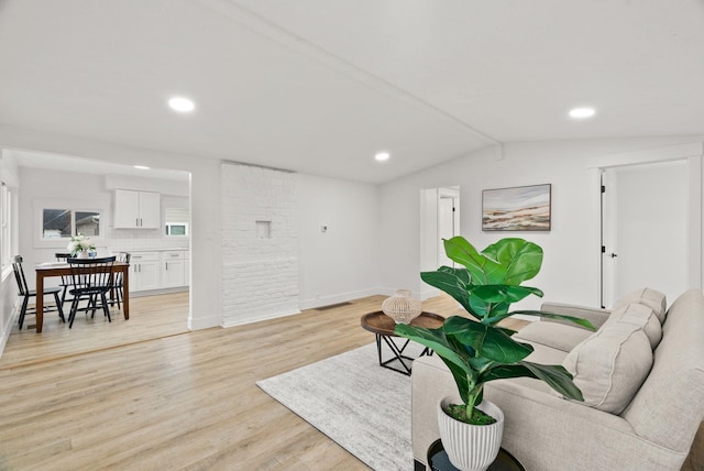 living room with light hardwood / wood-style floors and vaulted ceiling