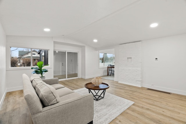 living room with light hardwood / wood-style floors, vaulted ceiling, and a healthy amount of sunlight