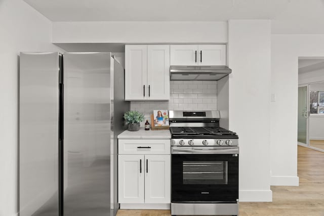 kitchen featuring decorative backsplash, white cabinets, light wood-type flooring, and appliances with stainless steel finishes