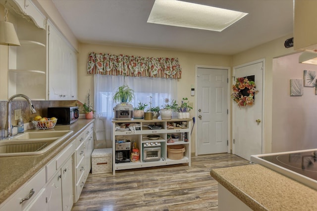 kitchen with range, white cabinetry, sink, and hardwood / wood-style flooring