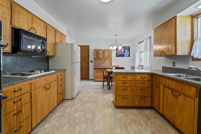 kitchen featuring black appliances, sink, hanging light fixtures, kitchen peninsula, and a chandelier