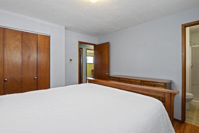 bedroom featuring connected bathroom, a closet, a textured ceiling, and hardwood / wood-style flooring