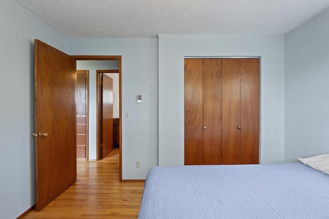 bedroom with a closet, a textured ceiling, and light wood-type flooring