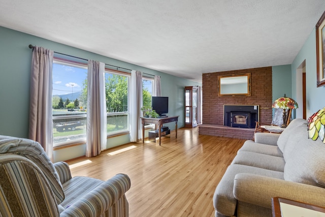 living room featuring a fireplace, light hardwood / wood-style floors, and a textured ceiling