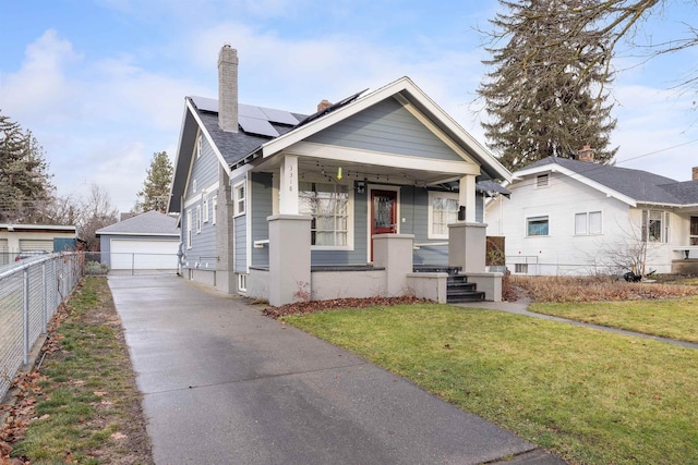 bungalow with solar panels, an outbuilding, a front yard, a porch, and a garage