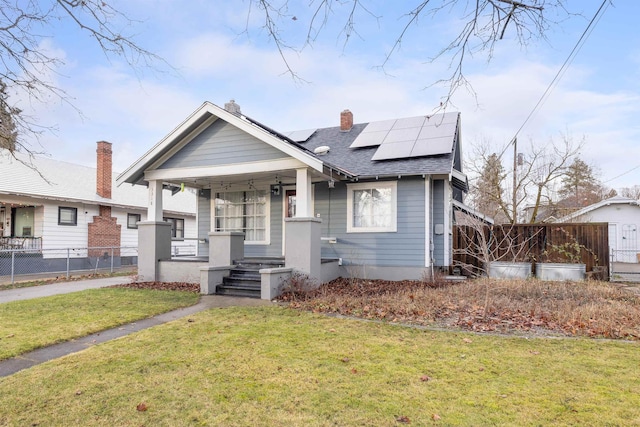 bungalow-style house with solar panels, a porch, and a front lawn