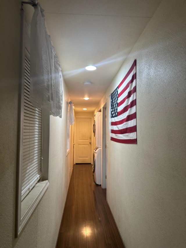 hall with hardwood / wood-style floors and stacked washer and clothes dryer