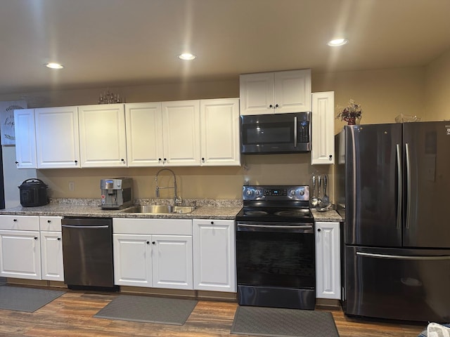 kitchen with sink, light stone counters, dark hardwood / wood-style floors, white cabinets, and appliances with stainless steel finishes