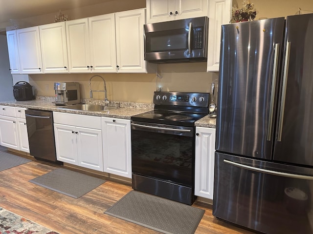 kitchen featuring black appliances, white cabinets, sink, and hardwood / wood-style flooring