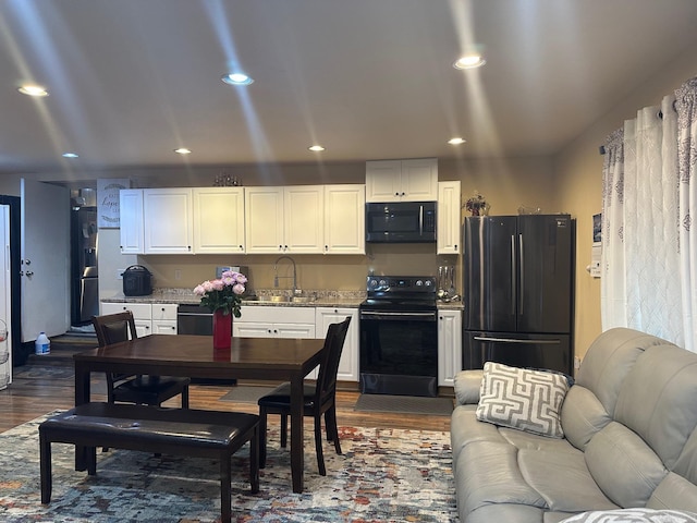 interior space with black appliances, white cabinetry, sink, and dark wood-type flooring