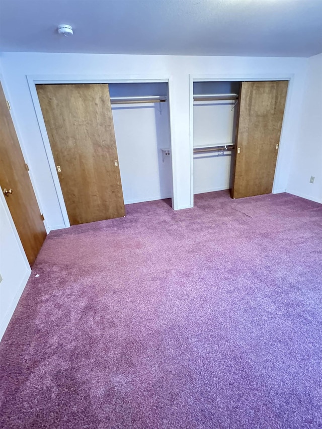 unfurnished bedroom with carpet floors and two closets