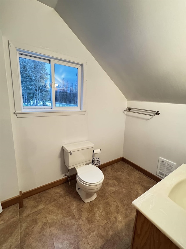 bathroom featuring vanity, vaulted ceiling, and toilet