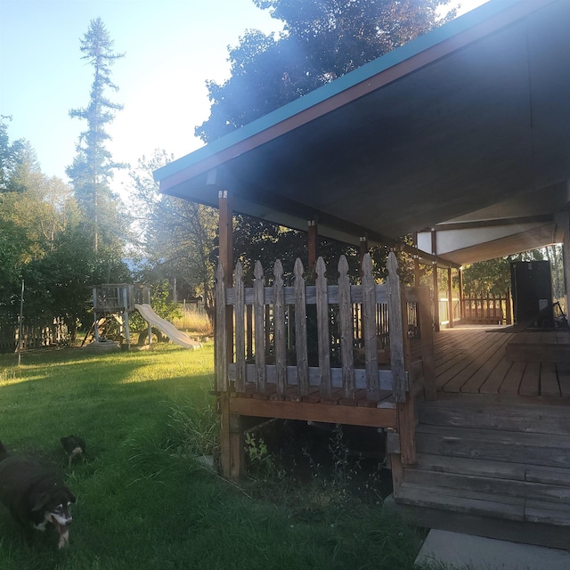 wooden terrace with a playground and a lawn