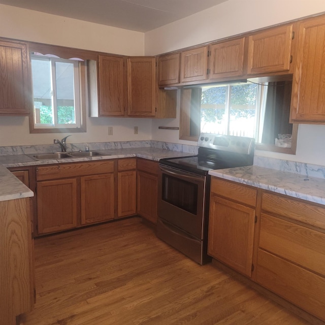 kitchen featuring plenty of natural light, light wood-type flooring, electric stove, and sink