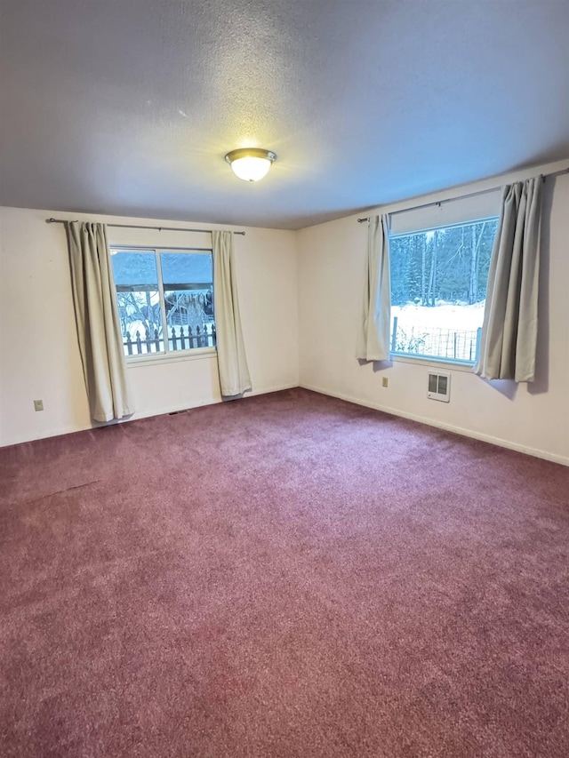 carpeted empty room featuring a textured ceiling