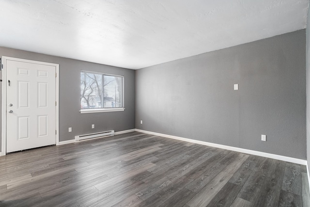 empty room with dark hardwood / wood-style floors and baseboard heating