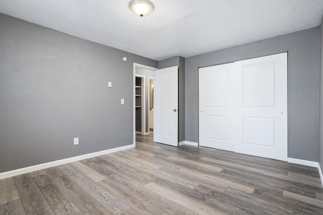 unfurnished bedroom featuring wood-type flooring and a closet