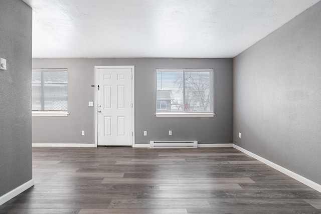 foyer entrance featuring a healthy amount of sunlight, dark hardwood / wood-style floors, and a baseboard heating unit