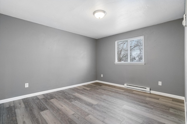 empty room featuring hardwood / wood-style flooring and baseboard heating