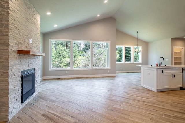 unfurnished living room with a fireplace, light hardwood / wood-style floors, an inviting chandelier, and sink