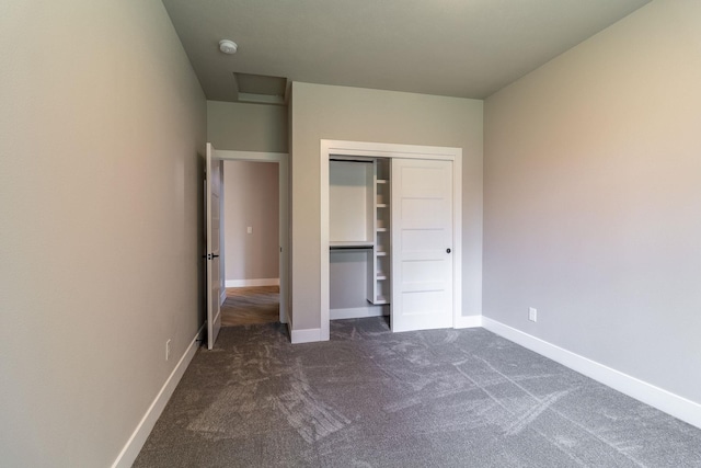 unfurnished bedroom with dark carpet and a closet