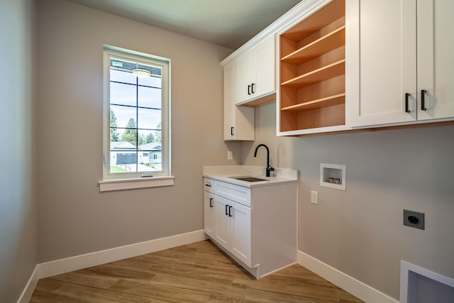 laundry room with hookup for an electric dryer, hookup for a washing machine, cabinets, sink, and light hardwood / wood-style floors