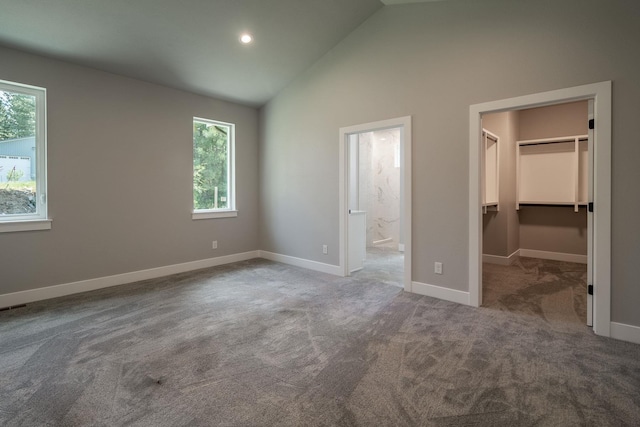 unfurnished bedroom with carpet, a closet, a walk in closet, and multiple windows