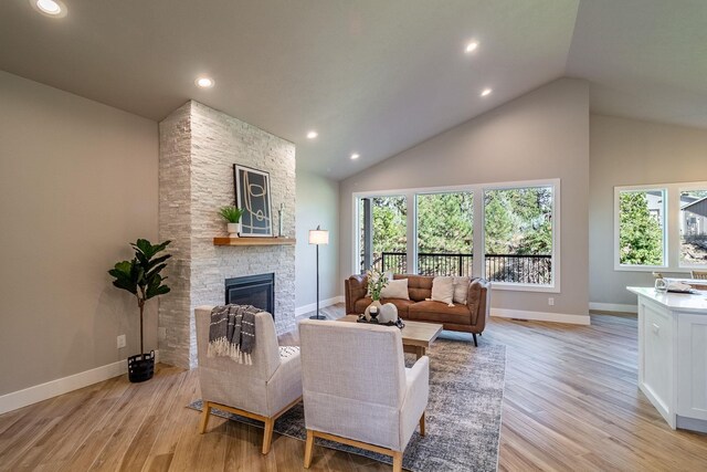 living room with light hardwood / wood-style floors, a fireplace, and high vaulted ceiling